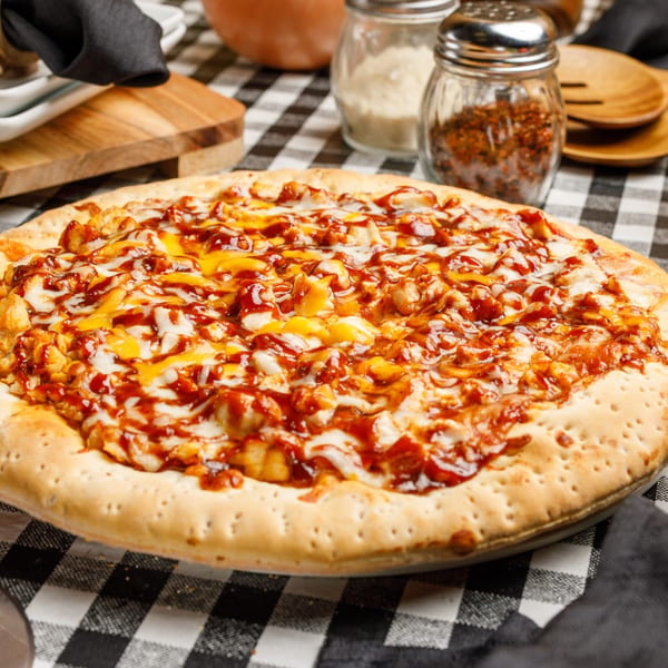Pete's Pizza BBQ chicken pizza with cheese and sauce on a black and white checkered tablecloth.