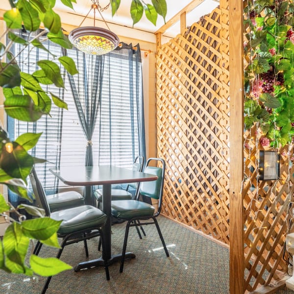 Cozy dining area at Pete's Pizza with a table, chairs, window blinds, and decorative lattice.