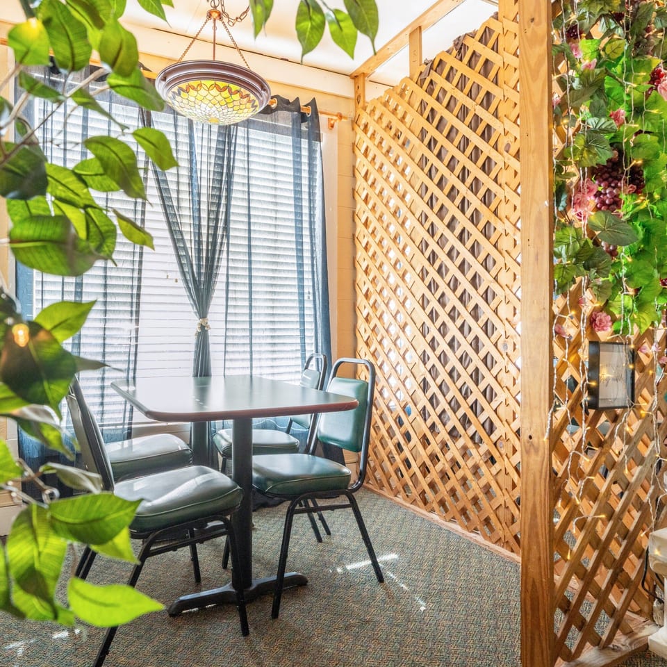 Cozy dining area at Pete's Pizza with a table, chairs, window blinds, and decorative lattice.