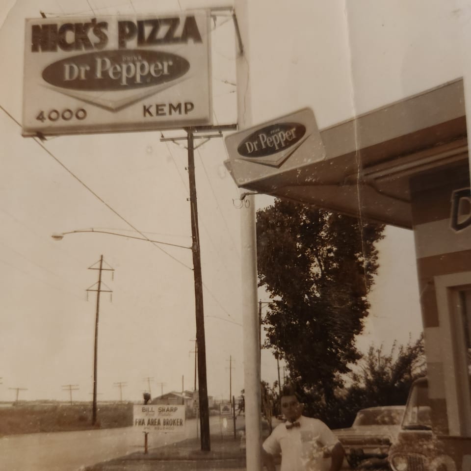 Vintage photo of Nick's Pizza sign with Dr Pepper logo, a man, and cars on a street.